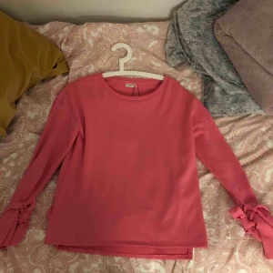  - En rosa tröja med knytningar vid handlederna 