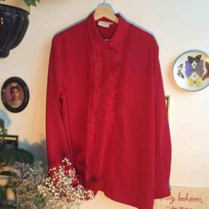 Röd skjorta/blus med vackra detaljer. Superfin nyans. Är en large, men funkar även för mindre storlekar, då mer som en oversize-skjorta. Cool och bohemiskt fin, kan ex. bäras snyggt instoppad till en lång kjol!