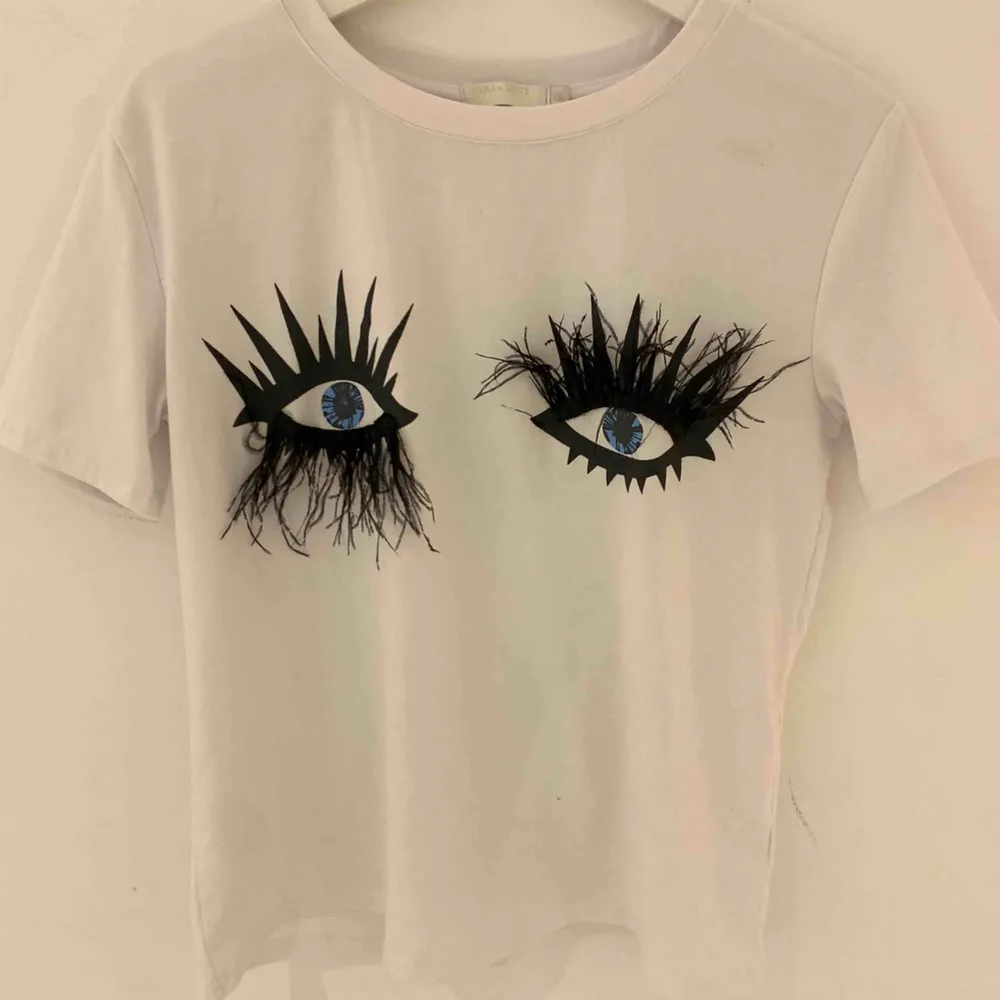 T-shirt med ögon och fjäderfransar Köpt i butik i Frankrike! Använt 2 ggr.  Funkar toppen för mig som har strl S😊. T-shirts.