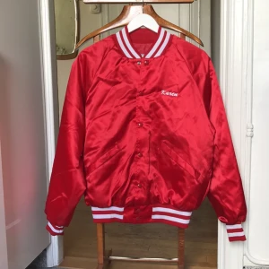  - Röd glansig baseball jacka. Second hand i storlek M (passar även storlek S och blir då lite mer baggy modell). 