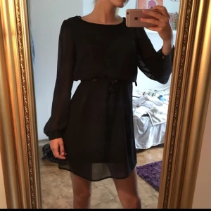  - Svart klänning med guldknappar vid rygg och ärmslut som detaljer. Tyget är mesh-aktigt men överallt utom ärmarna finns ett svart undertyg. Köparen står för frakt! (Skärpet på bild 1 ingår ej)