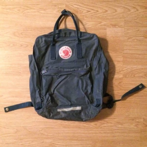  - 💎Kånken BIG i mörkblått/grått utförande, din nya bästavän i alla tillfällen! Är du grym på Tetris kan du få plats med hur mycket som helst i ryggan! Från Fjällräven såklart. Storlek 17" datorn får plats, sök mått på hemsidan. Köpt 2hand & välanvänd men har mer att ge! Pyttehål på ryggen, bild 2&3. Saknar sittunderlag, oskriven namnlapp! Frakt: +53kr spårbart.💎