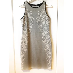  - Fodralklänning från vila. Grått tyg med blommdetaljer på och skinndetaljer vid axlarna. Pris exklusive frakt. 