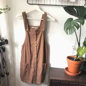  - Sååå söt brun hängsel-klänning i manchester från Pull&bear. Jag köpte den här på Plick, men har inte använts mer än 5 gånger totalt. Säljer pga tycker den är lite kort på mig som är 1.70 m. (Första bilden är tagen från tidigare säljare)