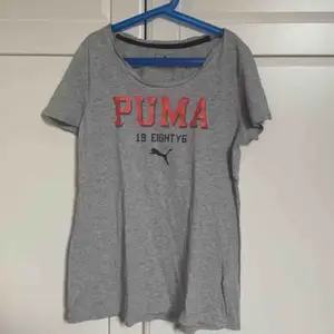 En grå kortärmad PUMA tröja som går till början av låret för mig som är 159cm lång. Den har en urringning. Använt få gånger. 