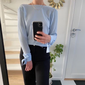 Fin ljusblå blus med en fin rygg 💙 - Här är en jätte fin ljusblå blus från NELLY som aldrig är använd💓. Rosetter på ryggen som gör den så fin. Xs är storleken men jag bär ivanliga fall S och den passar perfekt på mig💙. Köparen står för frakten.💝