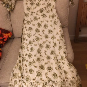 Långklänning från 70-talet - Lång klänning (cirka 135) med trumpetärm, knytskärp och volang längst ned. Har insydd underkjol och är därför inte transparent. Märkt storlek 38 men är snarare 34-36 (inte stretchig). Terylene och bomull. Frakt tillkommer.