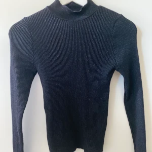 Snygg svart topp🖤 - 🖤Snygg polotröja/tröja i svart med glitter. Se andra bilden för att se det glittriga. Köpt i Stradivarius/Spanien. Fin öppning vid änden av armen. Smal passform. 