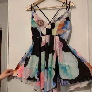 Blommig klänning  - Klänningen är kortare på sidorna och längre fram- och baktill. Den är srl M men är väldigt liten så skulle säga XS/S. Sitter smickrande på. (+frakt) 