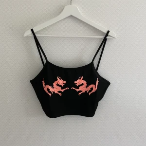 Svart magtröja - Svart magtröja med snygga drakar på från SHEIN:) Den har något långa band så den sitter bäst på någon med lite större byst! Annars går det såklart att korta ner banden själv om man knyter eller syr etc. Storleken är S men den passar även M-L! Frakt: 11kr