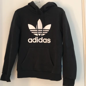 Hoodie från Adidas, strl 34 - Svart Adidas-hoodie som är i helt ok skick pga att den är använd en del. Frakt ingår inte i priset.