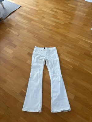 Kräm vita  bootcut jeans från Divided - Säljer ett par kräm vita bootcut jeans från Divided. De har klassisk femficksmodell, normal midja och utsvängda ben. Perfekta för dig som vill ha en clean och fräsch look med lite retrovibbar. Materialet är mjukt och bekvämt bomullstyg. Är 42 men sitter som en 40 