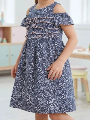 Blå blommig offshoulder klänning - Söt blå klänning med vitt blommönster och offshoulder-design. Klänningen har volangdetaljer framtill och kort ärm med öppen axel. Perfekt för sommarens alla tillfällen.