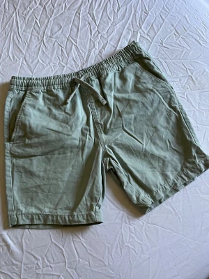 Ljusgröna shorts med snörning - Ett par ljusgröna shorts med elastisk midja och snörning framtill.