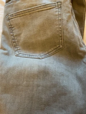 Grå bootcut jeans  - Snygga grå jeans med klassisk femficksmodell och raka ben. Jeansen har bälteshällor, dragkedjegylf och knappstängning. Tillverkade i mjuk denim med en lätt tvättad look. Perfekta för en avslappnad stil.