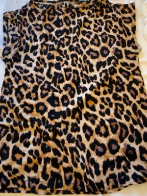 Leopardmönstrad ärmlös topp - Snygg ärmlös topp med leopardmönster i beige, brunt och svart. Perfekt för dig som vill sticka ut och addera lite edge till din outfit. Mjuk och lätt i materialet, passar till både jeans och kjol. S-M!