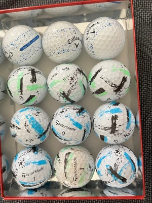 Golfbollar TaylorMade & Callaway - Säljer ett set med vita golfbollar från TaylorMade och Callaway. Bollarna har färgmarkeringar i blått, grönt och svart, vilket gör dem lätta att känna igen på banan. Perfekt för dig som vill ha unika golfbollar till nästa runda.