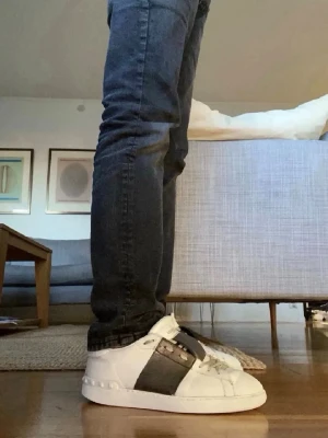 Valentino opens - Snygga vita valentino sneakers med bred svart läderdetalj över mitten och vita snören. Skorna har en klassisk låg profil, perfekt för en stilren look perfekta nu till sommaren. Materialet är läder och designen är enkel men modern.      ‼️OBS box och dustbag ingår inte‼️kvitto går att få. Bara att höra av dig vid funderingar