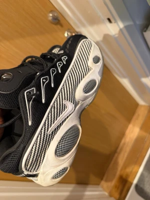 Nike svartvita sneakers med mönster - Säljer ett par unika svartvita Nike sneakers med grafiskt mönster på sidan och vit sula med svarta detaljer. Skorna har lågt skaft, mesh- och syntetmaterial samt tydlig Nike-logga på sidan. Snygga detaljer på snörningen och cool retrostil.