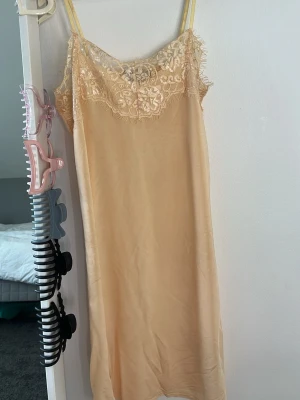 Beige nattlinne med spetsdetaljer - Elegant nattlinne i beige med tunna axelband och vacker spets upptill. 
