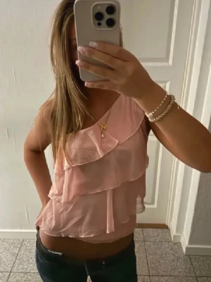 Ljusrosa oneshoulder volangtop - Säljer denna trendiga one- shoulder topp. Storlek 152 men passar xs-s