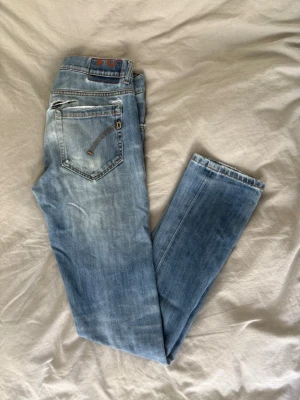 Dondup jeans - Snygga ljusblå skinny george jeans från Dondup   med klassisk femficksdesign och slitna detaljer vid fickorna. Jeansen har en smal passform och är tillverkade i denim med en lätt tvättad look. Perfekta för en avslappnad och trendig stil. Jeansen är äkta men har tyvärr ett hål över den högre fickan, därav priset. Hålet är ganska diskret och folk märker knappast av de. Priset kan alltid diskuteras, skriv frågor om det finns några!