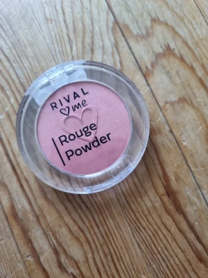 Rival Me Rouge Powder rosa - Rouge i puderform från Rival Me i en fin rosa nyans. Kommer i en rund, genomskinlig plastförpackning med lock. Perfekt för att ge kinderna en fräsch och naturlig färg. Vegansk formula.