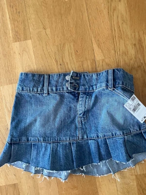 Blå jeanskjol med volangkant - Trendig blå lågmidjade jeanskjol med volangkant. Helt ny från Mango med lappen kvar, köptes för 500