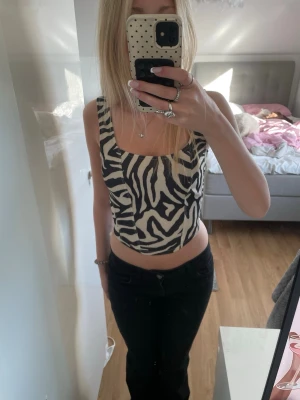 Zebramönstrad croppad topp - Snygg croppad topp med zebramönster i svart och vitt. Toppen har breda axelband och fyrkantig ringning både fram och bak. Perfekt för dig som vill sticka ut med en trendig och djärv look. Funkar på fest och till vardags😜