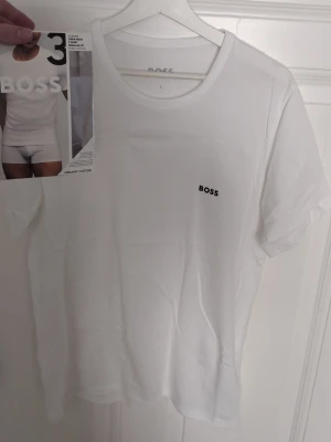 Vit t-shirt från BOSS i bomull - Vit t-shirt från BOSS med liten svart logga på bröstet. Helt ny, har aldrig använt. Passar inte min passform och därav säljer till någon som det passar bättre till, Skriv vid funderingar 
