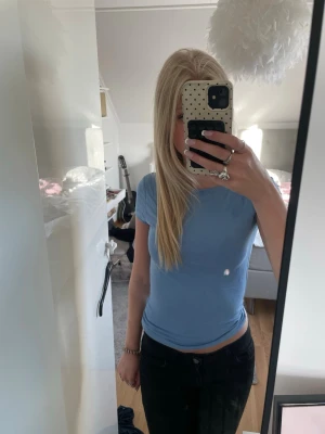 Ljusblå topp med öppen rygg - Snygg ljusblå topp med korta ärmar och en djup öppen rygg. T-shirten har en tight passform som framhäver figuren. Perfekt för dig som gillar en enkel men ändå unik stil.