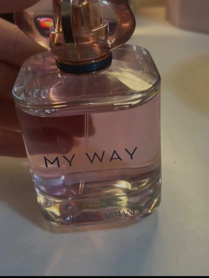 Giorgio Armani My Way parfym - Säljer en elegant parfym från Giorgio Armani, My Way. Flaskan är genomskinlig med ljusrosa doftvätska och har en stilren, fyrkantig form med rundade kanter. Locket är exklusivt designat med gulddetaljer. Perfekt för dig som gillar fräscha och feminina dofter.