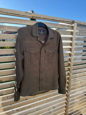Grön overshirt - Tjena! Säljer nu denna extremt snygga linne overshirten ifrån märket bondelid! Storlek S (passar mig som är 187) Färg: mörkgrön  Material: 100% lin Längd baksida: 75cm Länge framsida: 72,5cm Inga fläckar eller liknande! Köpt på MQ för 999kr!