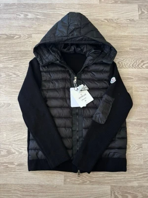 Svart cardigan jacka från Moncler - Svart cardigan jacka från Moncler med stickade ärmar. Har NFC märke för webbplats och är perfekt för våren.