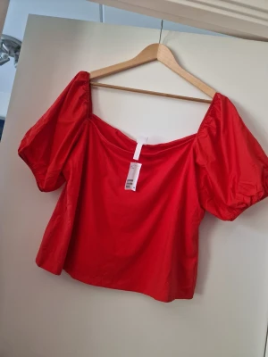 Röd offshoulder topp från H&M - Trendig röd offshoulder topp från H&M med puffiga korta ärmar och luftig passform. Tillverkad i mjukt bomullsmaterial som känns skönt mot huden. Perfekt för dig som vill sticka ut med en färgstark och modern look.