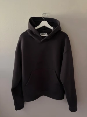 Svart hoodie från Weekday - En stilren svart hoodie från Weekday med klassisk huva och stor magficka framtill. Hoodien har en relaxed fit och är gjord i mjukt bomullsmaterial. Perfekt för en chill och avslappnad look.