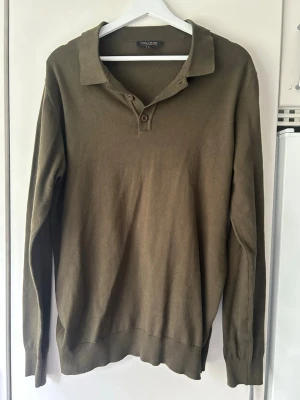 Olivgrön långärmad tröja  - Olivgrön långärmad tröja från indicode med krage och två knappar vid halsen. Använd en hand full gånger och är i mycket gott skick. Storlek M