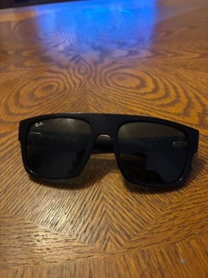 Svarta smarta glasögon från Ray-Ban - Ray-Ban smarta glasögon med klassisk svart båge i plast och integrerade teknikfunktioner. Glasögonen har diskret design med knappar på skalmarna och är perfekta för dig som vill kombinera stil med smarta funktioner.