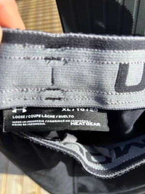 Svarta träningsshorts Under Armour - Svarta träningsshorts från Under Armour i loose fit med elastisk midja och stort logotryck längs ena benet. Tillverkade i lätt och snabbtorkande HeatGear-material som passar perfekt för aktiva dagar.