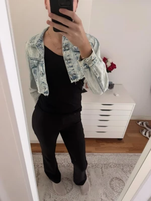 Ljusblå croppad jeansjacka - Trendig ljusblå croppad jeansjacka med klassisk krage och knappar framtill. Jackan har en snygg tvättad look och raka ärmar. Perfekt för att lyfta vilken outfit som helst.