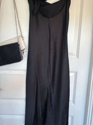 Svart långklänning i satin - Gina tricot  - Elegant svart långklänning med slits på sidan. Klänning är axelbandslös med möjlighet till en fin rosett på ryggen 💕klänningen är från Gina tricot i storlek xs. Perfekt till bal eller annat liknande
