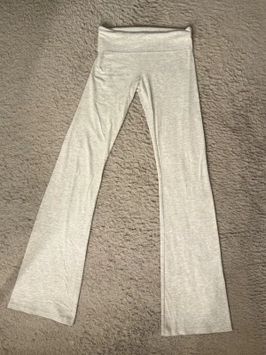 Grå bootcut leggings från Nelly - Säljer dessa ursnygga lågmidjade ljusgrå yogapants från Nelly med bootcut. Byxorna har mjukt och stretchigt material som sitter skönt på kroppen. Perfekta för en avslappnad och trendig look.
