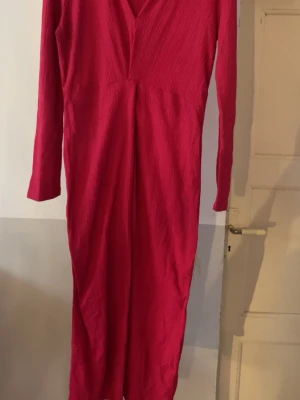 Rosa långärmad klänning Gina Tricot - Säljer en snygg rosa långärmad klänning från Gina Tricot. Klänningen har v-ringning och är i ett lätt strukturerat tyg som ger en cool känsla. Perfekt för dig som vill sticka ut med färg och stil.
