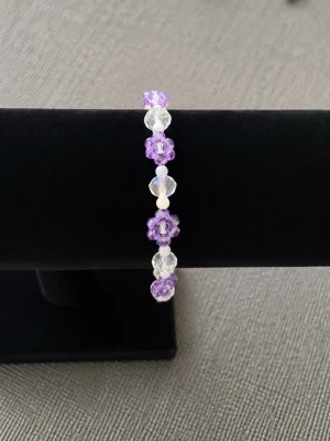 Lila och vita pärlarmband - Ett armband med lila och vita pärlor i blommönster och ett enkelt metallspänne. 