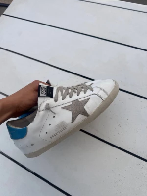 Golden Goose vita sneakers med blå häl - Säljer nu mina golden goose i storlek 43/43 på grund av att jag köpte fel storlek. Det är i bra skick och hör av er om ni vill ha fler bilder. pris går absolut att diskuteras!🙏🌊⚜️