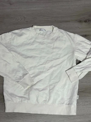 Vit sweatshirt från Selected Homme - Klassisk vit sweatshirt från Selected Homme med rund halsringning och ribbade muddar. Tillverkad i mjukt material som känns skönt mot huden. Perfekt för en clean och avslappnad stil.