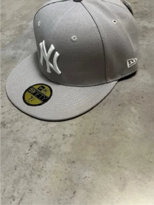 Grå New Era Yankees keps 39THIRTY - Snygg grå New Era 39THIRTY keps med vitt NY Yankees broderi framtill och MLB-logga bak. Klassisk rak skärm och ventilerande hål. Tillverkad i slitstark bomullsmix, perfekt för dig som gillar streetwear och sportig stil.
