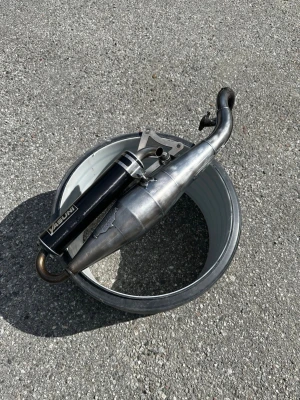 Svart och silver Yasuni moppeavgassystem - Säljer ett Yasuni avgassystem till moped i svart och silver. Tillverkad i metall med en sportig design och tydlig Yasuni-logga på ljuddämparen. Komplett med fäste och böjd rörform som passar de flesta mopeder. Perfekt för dig som vill ha bättre prestanda och snygg look.