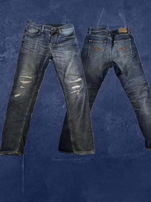 Nudie Jeans Steady Eddie II  - Ett par Nudie Jeans Steady Eddie II i storlek 31/32 med perfekt inarbetad vintagekänsla. Jeansen har snygga vita slitningar där tidigare hål har reparerats, vilket ger dem en unik och autentisk look med mycket karaktär. Bekväm passform och klassisk tvätt som funkar till allt.  Mått 📏   Midja 43 cm  Längd 108 cm   Lårbredd 30cm