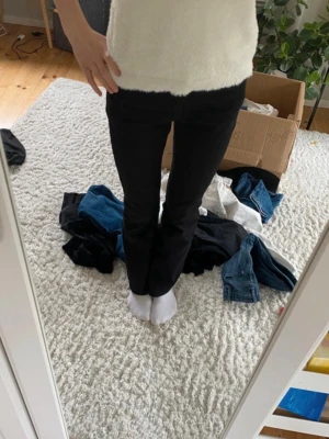 Svarta bootcut jeans - Säljer ett par svarta bootcut jeans med klassisk femficksdesign och normal midja. Jeansen har en snygg passform som sitter tajt över låren och släpper ut vid vaden. Perfekta till sneakers eller boots.